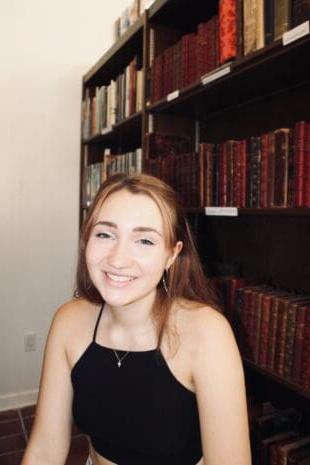 W&大四学生Lily Bonasso坐在书柜前微笑着.